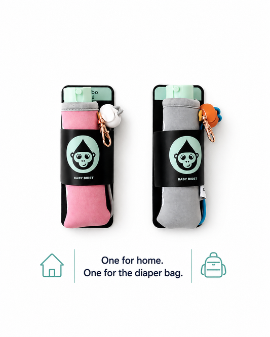 Two baby bidets one gray and one pink in their packaging. Text at the bottom that says one for home. one for the diaper bag. 