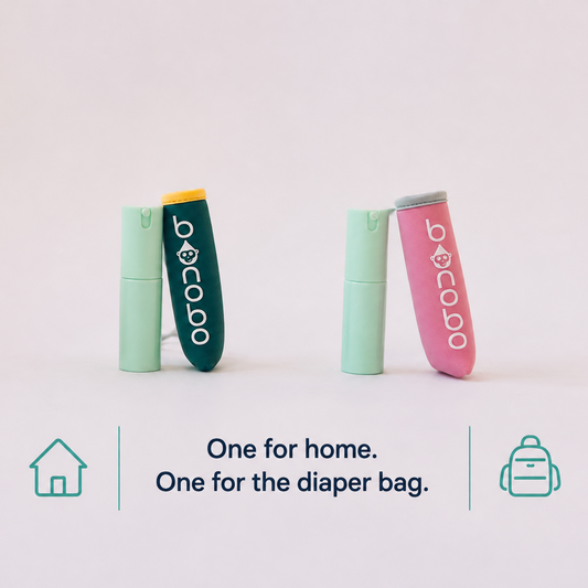 Two small baby bidets, one mint green and one pink, standing upright on a white background with text below reading 'One for home. One for the diaper bag.